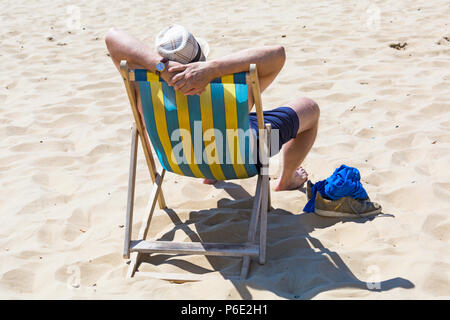 Bournemouth, Dorset, UK. 30th June 2018. UK weather: the heatwave continues and another hot sunny day at Bournemouth beaches. Mid morning and the beaches are getting packed as sunseekers head to the seaside. A slight breeze makes the heat more bearable. Man soaking up the sun sitting in deckchair deck chair. Stock Photo