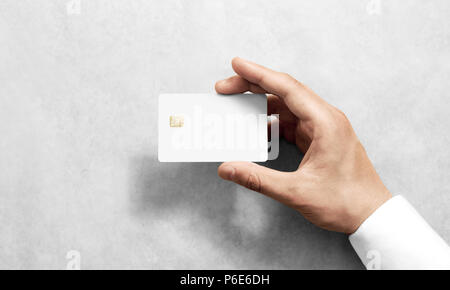 Hand holding blank white credit card mockup with rounded corners. Plain creditcard mock up template with electronic chip holding arm. Plastic bank-card display front design. Business branding. Stock Photo
