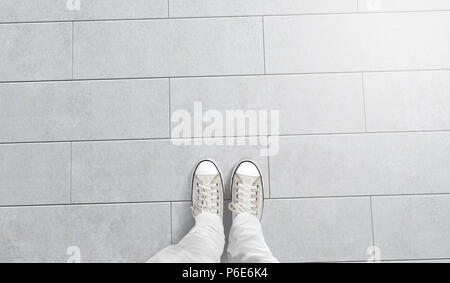 Person taking photo of his foots stand on blank floor, isolated, top view, clipping path. Ground design mock up. Man wear gumshoes and watching down. Deck flooring mockup template. Stock Photo