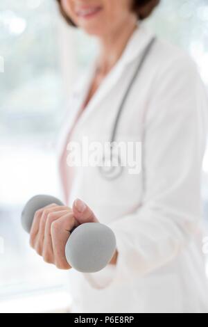Female doctor holding hand weight. Stock Photo
