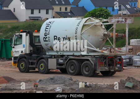 A building site cement mortar mixing unit just being taken away on the back of a specialised transport lorry with the building site being closed. Stock Photo