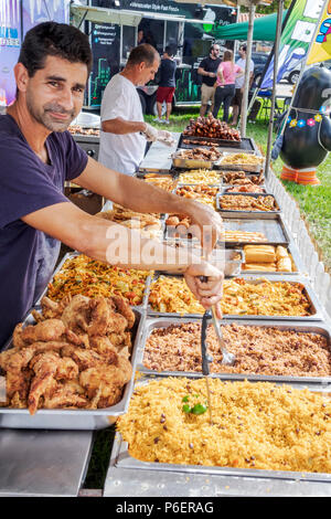 Florida,Coral Gables,Hispanic Cultural Festival,Latin American food vendor stall tent,display sale,Hispanic man men male,food trays,fried chicken,rice Stock Photo