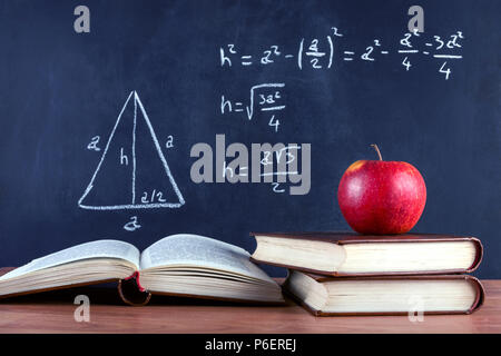 Red apple on books and blackboard with Pythagorean theorem written by chalk. School classroom and education concept. Close up, selective focus Stock Photo