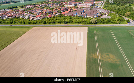 Aerial view of a suburb on the outskirts of Wolfsburg in Germany, with terraced houses, semi-detached houses and detached houses, arable land in the f Stock Photo