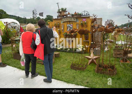 2 women standing, looking at display of garden sculpture & ornaments on stall at RHS Chatsworth Flower Show, Chatsworth House, Derbyshire, England, UK Stock Photo