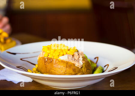 Stuffed potato with tuna and sweetcorn on white plate selective focus Stock Photo