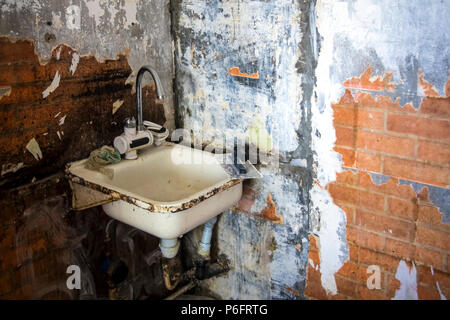 dirty old washbasin on the background of ripped walls, the concept of repair Stock Photo