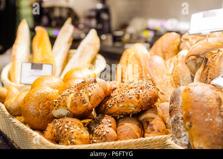 Close up freshly baked pastry goods on display in bakery shop. grocery market. Fresh bread, buns and rolls in wicker basket. Selective focus. Copy space. Stock Photo