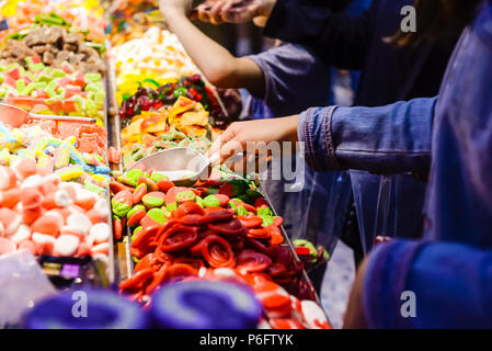 Customers choose sweets from counter with assorted colorful different shape jelly candies on market place in Tel Aviv, Israel. Selective focus, space for text. Stock Photo