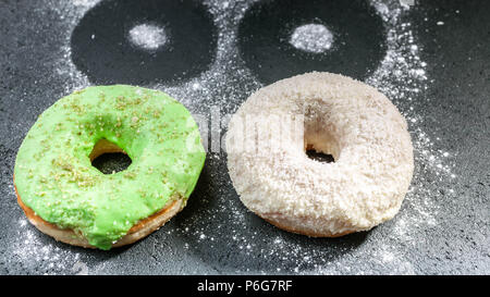 Two donuts with colorful icing on a dark background. Stock Photo