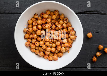 Chickpeas with chili spice and olive oil in bowl on black rustic table close up top view image Stock Photo