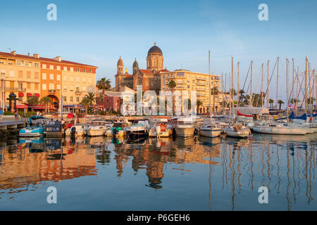 The evening sun shines on the cathedral, seafront buidings and boats, Saint Raphael, France. Stock Photo