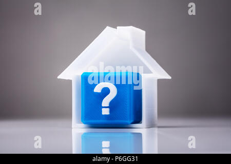 Blue Cube With Question Mark Sign Inside House Model On Reflective Background Stock Photo