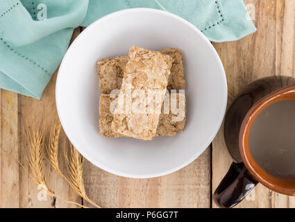 Wheat biscuit breakfast cereal raw in bowl on rustic wooden table - top view photograph Stock Photo