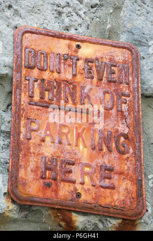 “Don’t even think of parking here”. Humorous No Parking message on a rusty textured old metal sign. Isle of Portland, Dorset, England, United Kingdom. Stock Photo