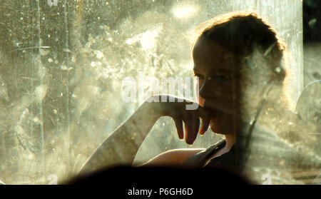 Belgrade, Serbia - May 29, 2018 : Blurry soft portrait of young blond teenage girl sitting and daydreaming while riding in a window seat of a bus on a Stock Photo