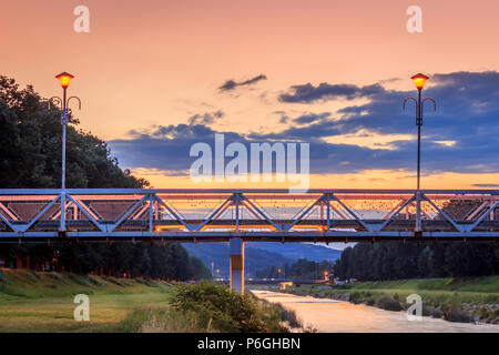 Love bridge in Pirot during colorful sunset with switched on romantic lamps love locks on the fence Stock Photo