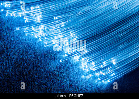 Bundle of optical fibers with lights in the ends. Blue background. Stock Photo