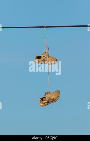 Pair of training shoes hanging over a telephone wire, Cambridgeshire Stock Photo