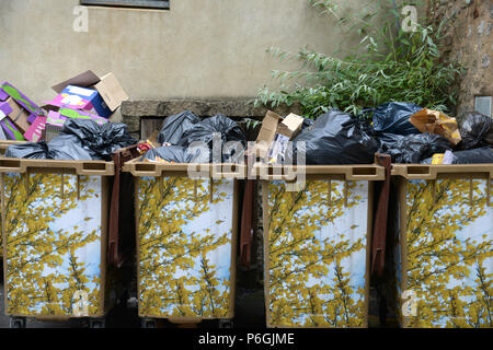 4 rather full wheelie waste bins covered in plastic images of woodland scene in france Stock Photo