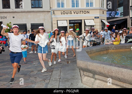 Happy students celebrate their high school graduation and run or dance round the Stork Fountain, Storkespringvandet, in Copenhagen before plunging in. Stock Photo