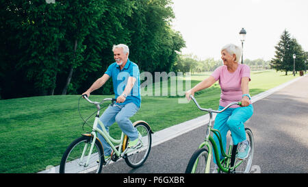 Senior couple riding bicycles on green park Stock Photo