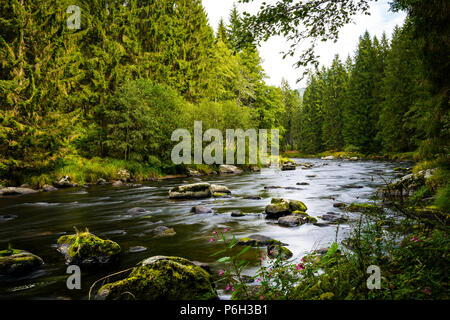 River with stones in the water and reflection on the creek and clouds on the sky in the bavarian forest Stock Photo