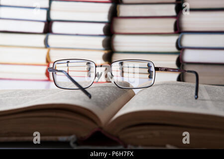 glasses lying on a book on background of stacks of books Stock Photo