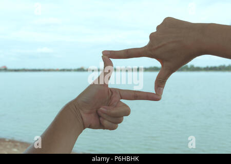 Close up of hands making frame gesture. Close up of woman hands making frame gesture with sunset. Stock Photo