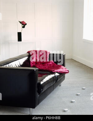 Crimson velvet throw on shiny black PVC upholstered in modern city living room Stock Photo