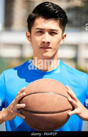 young asian male basketball player holding a ball looking at camera. Stock Photo