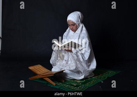 Little muslim girl reading Koran (Quran) Stock Photo