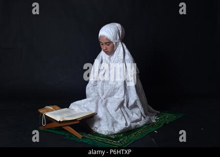 Little muslim girl reading Koran (Quran) Stock Photo