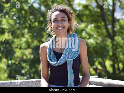 Beautiful Brazilian mixed race woman smiling outside in park Stock Photo