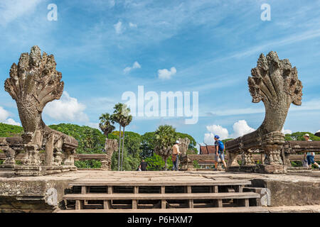 Angkor Wat, Cambodia - November 17, 2017: Tourists enter to Angkor Wat temple passing by nagas, snakes, monuments. It is the largest religious complex Stock Photo