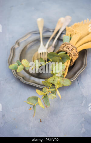 Rustic table setting with vintage silverware and plates on concrete table Stock Photo
