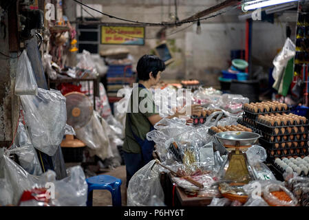 Thailand indoor market and female vendor surrounded by plastic bags ironically on International plastic bag free day 2018 Stock Photo