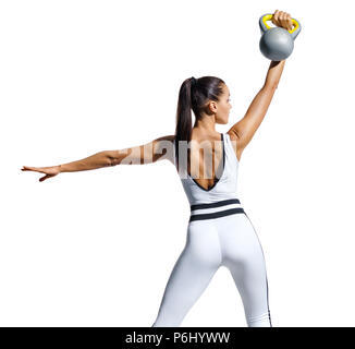 Strong woman training with kettlebell. Photo of woman in white sportswear isolated on white background. Strength and motivation. Rear view Stock Photo