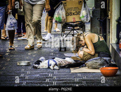 23 August 2014 - Sicily, Italy. Poor young homeless woman with the dog,  sitting and begging for money in the busy street of the coastal city of Catania Stock Photo