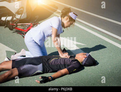 Female nurse helping emergency CPR to asia cyclist injured on the street bike after collision accident car and bike Stock Photo