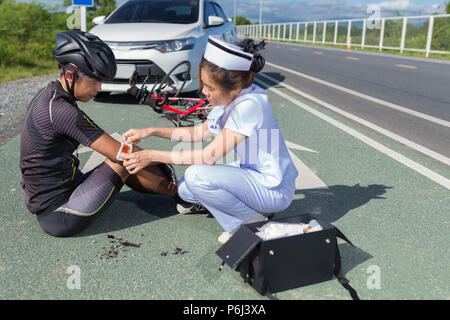 Female nurse helping emergency to asia cyclist injured on the street ...