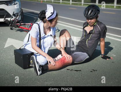 Female nurse helping emergency to asia cyclist injured on the street bike after collision accident car and bike Stock Photo