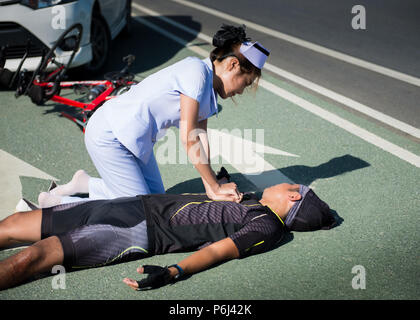 Female nurse helping emergency CPR to asia cyclist injured on the street bike after collision accident car and bike Stock Photo