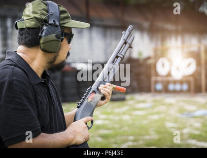 View of a man with a shotgun reload the cartridge. Stock Photo