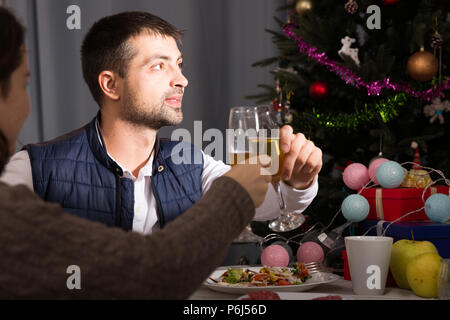 Family couple having christmas dinner with champagne and watching tv Stock Photo