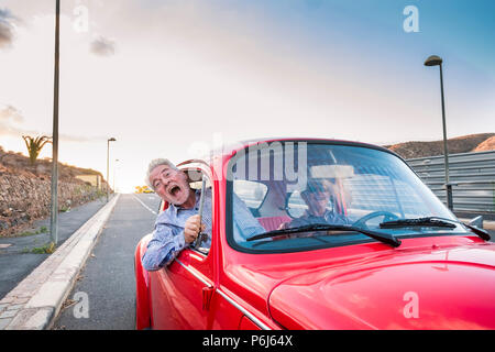 nice beautiful senior adult couple traveling together while the woman drive and the man shout for scare or for craziness. happiness and joy together f