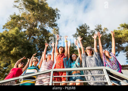 group of seven girls staying outdoor enjoying activity leisure in friendship all together. hands up to celebrate summer and vacation lifestle. colored Stock Photo