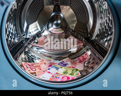 Money laundering symbol, chinese yuan banknotes in washing machine with the door open Stock Photo