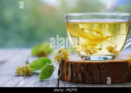 Cup of fresh tea made from linden leaves on a wooden stand close-up with space for text Stock Photo