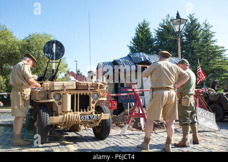 Kidderminster, UK. 30th June, 2018. AA journey back in time begins on the Severn Valley Railway as we turn the clock back to the 1940s. Visitors and staff pull out all the stops to ensure a realistic wartime Britain is experienced on this heritage railway line. Here an American 1943 Willy's MB jeep (in desert sand colour) is being closely inspected amongst other military light utility vehicles on display outside the Kidderminster vintage train station. Credit: Lee Hudson/Alamy Live News Stock Photo